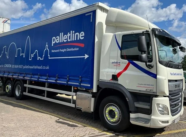 A Palletline Whitehead lorry parked outdoors on a sunny day, featuring a blue trailer with the London skyline graphic and the tagline “Network Freight Distribution”.